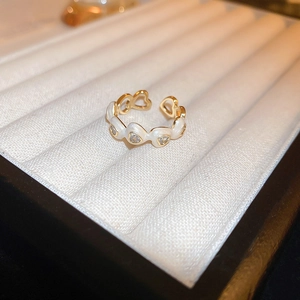 Close-up of gold-plated dragon heart ring with white enamel and rhinestones in a gift box