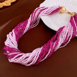 Multi-layer pink beaded necklace with gold clasps on an elegant white textured plate
