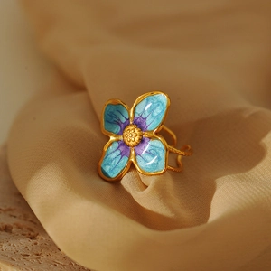 Macro shot of gold stainless steel ring featuring blue and purple enamel flower petals