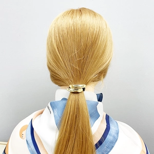 Golden metallic hair tie cuff on blonde ponytail with stylish silk scarf accessory