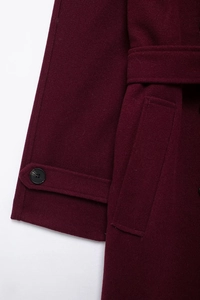 Détail du manteau en laine bordeaux montrant les coutures des poignets et de la ceinture