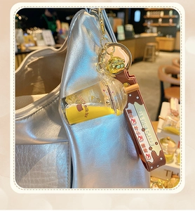 Detail of creative bear milk tea keychain hanging on a silver bag in a cafe