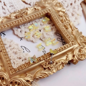 Detailed view of iridescent butterfly stud earrings placed in a vintage gold frame