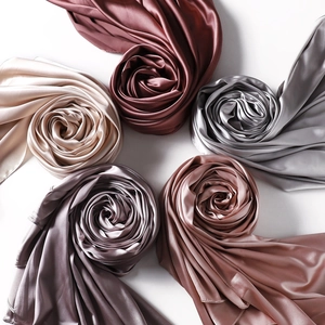 Detailed view of assorted satin scarves rolled into rose shapes showing silky gloss texture