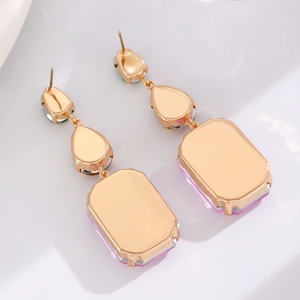 Detail of drop-shaped earrings with purple faceted gemstones and gold-plated finish