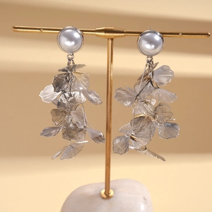 Close-up of pearl hollow mesh petal earrings on a gold T-bar display stand