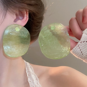 Close-up of oversized green translucent resin earrings with unique textured finish