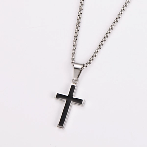 Macro detail of silver and black stainless steel cross pendant on polished metal chain