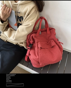 Detail of red canvas backpack with black buckle pocket on a grey bench in natural light
