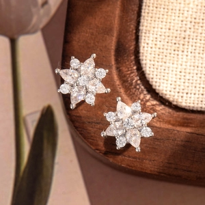 Elegante silberne Blumen-Ohrstecker mit funkelndem Zirkonia auf einem rustikalen Holztablett