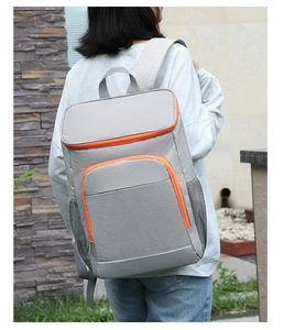 Outdoor waterproof insulated backpack in grey with orange zippers shown worn by a person