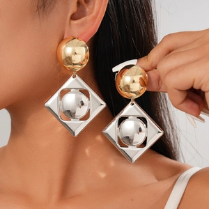 Chic geometric metal earrings with gold spheres and silver diamond frames on a model