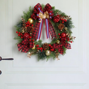 Close-up of Christmas wreath with red bows, pine cones and gold balls on white door