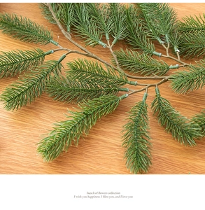 Detailed view of dense green PE pine needle branch on a warm brown wood background