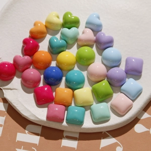Colorful heart and geometric resin beads on a white ceramic plate for DIY jewelry making