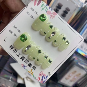 Vue détaillée de faux ongles faits main vert clair avec strass 3D et lignes argentées