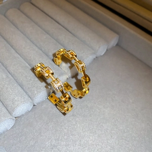 Macro view of gold-plated hoop earrings with micro-pave crystals and chain-link texture