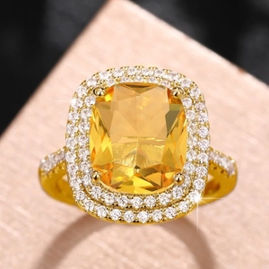 Close-up of golden cushion-cut yellow zircon ring with double-layered pavé diamonds