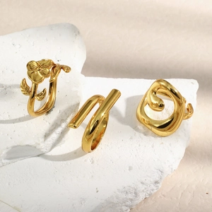 Detailed close-up of three 18K gold-plated floral and minimalist rings on white rock