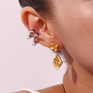 Gros plan de boucles d'oreilles dorées texturées et de bagues d'oreilles en perles