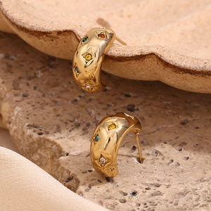 Macro detail of gold-plated hoop earrings with inlaid colorful zircon star accents