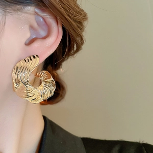 Close-up of golden irregular spiral pattern earrings with elegant metallic texture