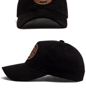 Dettaglio cappellino da baseball in camoscio nero con toppa circolare in pelle marrone