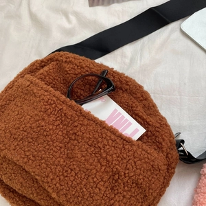Close-up of brown faux shearling crossbody bag with adjustable strap and front pocket