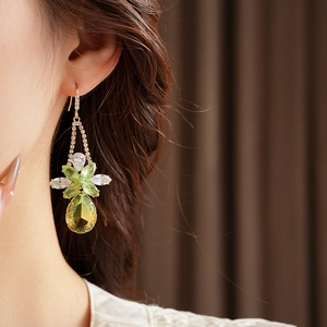 Close-up of elegant floral zircon drop earrings worn by model with sparkling green gems
