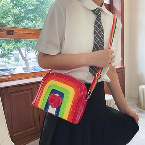 Rainbow striped crossbody bag with heart detail and adjustable strap shown on model