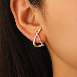 Macro detail of criss-cross curved earrings with gold finish and sparkling crystals