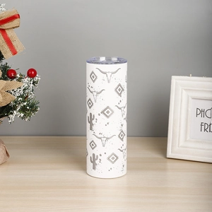 Detail of 20oz white tumbler with cow skull and cactus patterns on a wooden surface