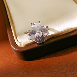 Gros plan d'une bague trèfle avec pierres bleu clair et anneau en métal torsadé chic