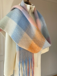 Detailed view of the fuzzy gradient plaid scarf with soft long tassels and plush texture