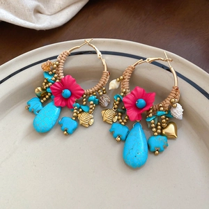Detail view of bohemian hoop earrings with fuchsia fabric flower and turquoise elephant charms