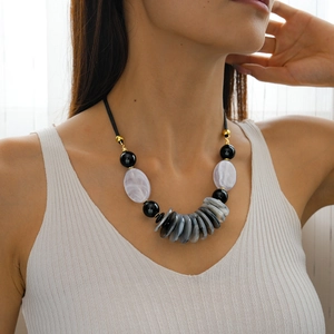 Close-up of marble pattern acrylic oval pendants on a black beaded choker necklace