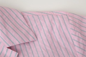 Détail du col et de l'épaule d'une chemise en popeline de coton rayée rose et bleue