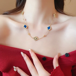 Detail of elegant gold-plated flower necklace with blue pendants on a female model