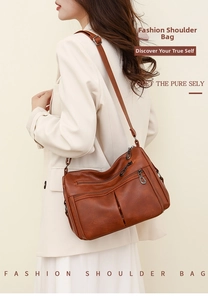 Close-up of vintage brown leather crossbody bag with multiple zippers and adjustable strap