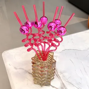 Detail of pink spiral disco ball straws in a glass bottle on marble surface