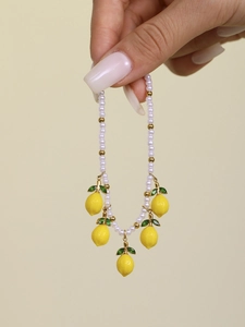 Detail view of handmade pearl bracelet featuring vibrant yellow lemon charms and golden beads