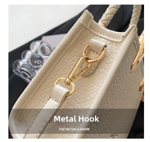Detail of cream crossbody bucket bag showing golden metal hardware and woven handle