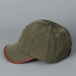 Détail de la casquette de baseball vert olive à séchage rapide avec bordure rouge-brun