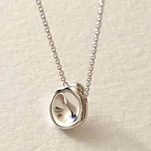 Macro shot of polished 925 sterling silver irregular pendant on a textured background