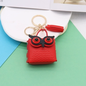Detail of red owl leather charm with lychee texture, golden keyring, and tassel