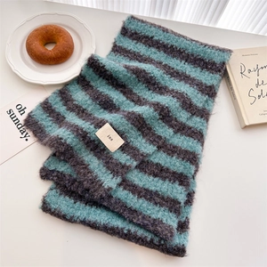 Close-up of soft blue and grey striped wool scarf with a woven ins label detail