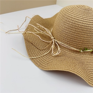 Detailed close-up of woven straw hat featuring a natural fiber band and wavy brim edge