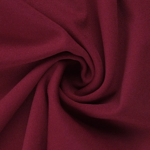 Macro du tissu de robe bordeaux montrant la texture et les plis élégants en spirale