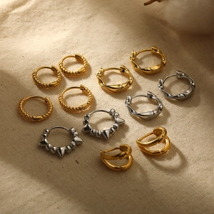 Polished 18k gold and silver Mobius twist hoop earrings on white linen fabric background