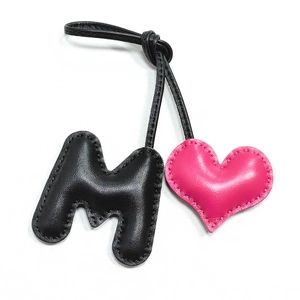 Handmade leather bag charm featuring black letter M and pink heart with fine stitching